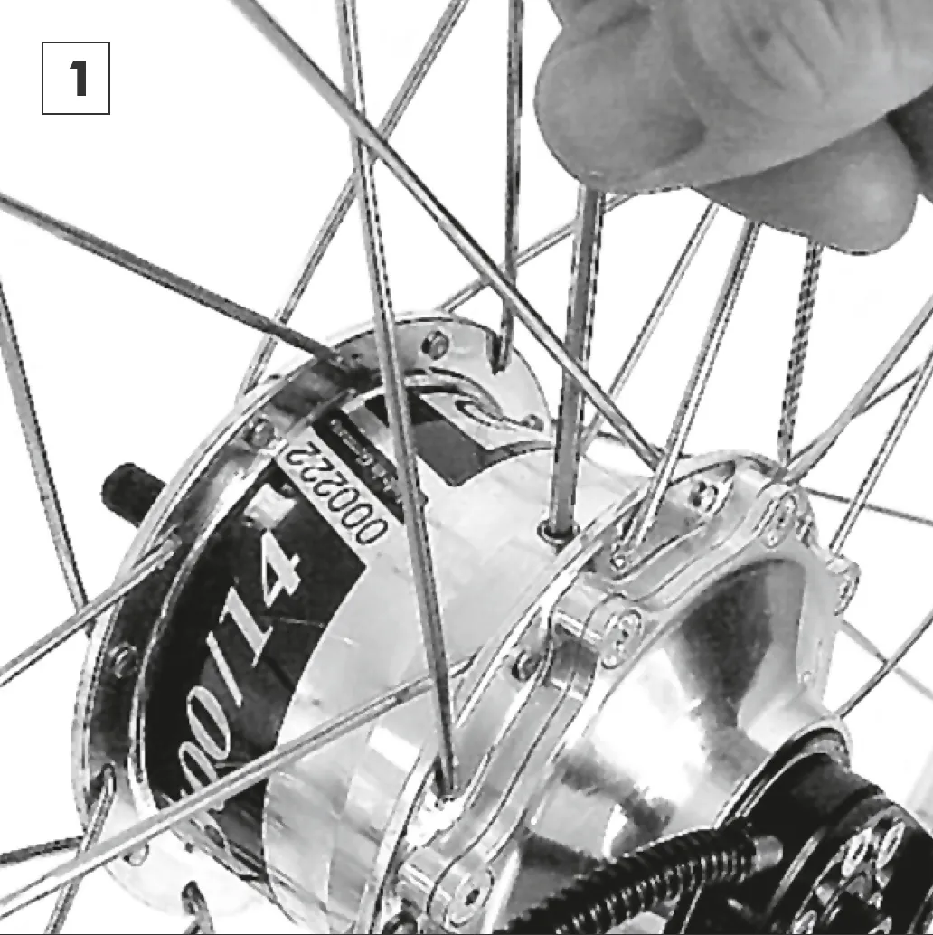 Unscrewing the oil drain screw with a 3 mm Allen key, with the screw pointing upwards.