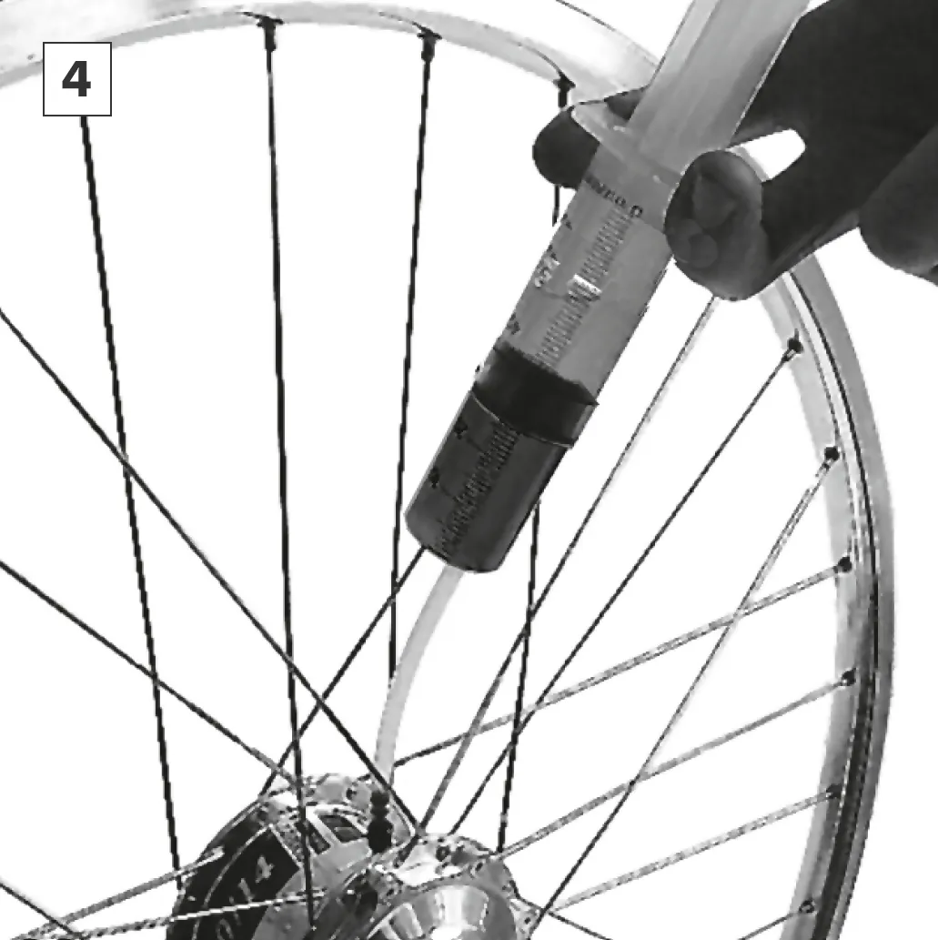 Pressing fresh SPEEDHUB OIL into the hub with the syringe.